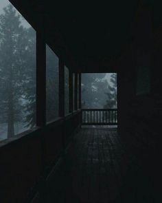 an empty porch in the middle of a dark forest at night with fog coming from the trees