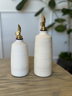 two white salt and pepper shakers sitting on top of a wooden table