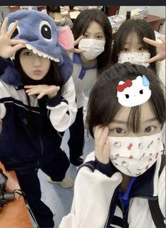 four girls wearing masks with hello kitty on their faces and one girl covering her eyes