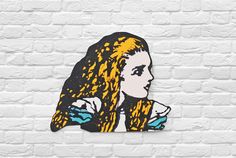 a painting of a woman with long hair on a white brick wall