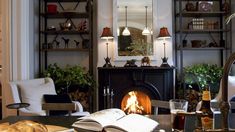 an open book on a table in front of a fire place and bookshelves