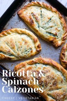 four baked pastries sitting on top of a baking pan covered in cheese and spinach