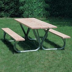 a wooden picnic table sitting on top of a lush green field