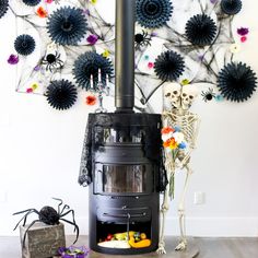 there is a skeleton sitting in front of a stove with decorations on the wall behind it