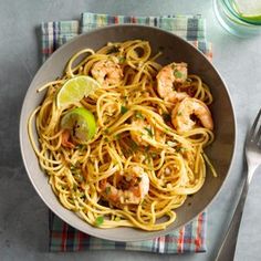 a bowl filled with pasta and shrimp on top of a table next to a fork