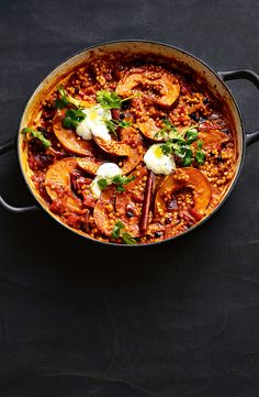 a large pot filled with food on top of a black table next to a knife