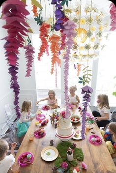 a group of children sitting around a wooden table with plates and cake on top of it