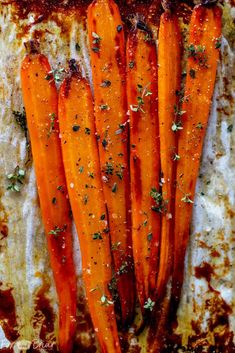 cooked carrots with herbs and seasoning sitting on a baking sheet, ready to be eaten