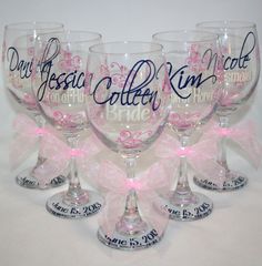 four wine glasses with pink bows and name on the glass are sitting side by side