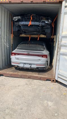 a car is in the back of a shipping container with it's hood open