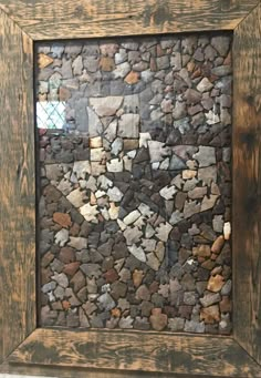 a wooden frame with rocks in it and a small window behind the frame that is made out of wood