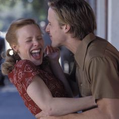 a man and woman laughing while standing next to each other