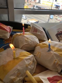 several wrapped sandwiches with lit candles in front of a window