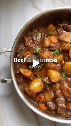 beef and guinness stew in a pot on a marble counter top with the words beef and guinness written above it