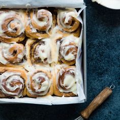 a box filled with cinnamon rolls covered in icing