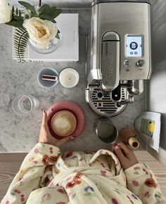 a woman is laying in bed with her feet on the table next to an espresso machine