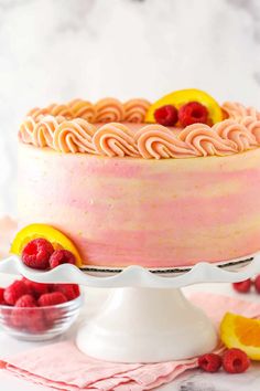 a close up of a cake on a plate with raspberries and lemons