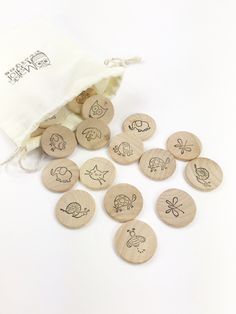 wooden buttons with drawings on them sitting next to a drawstring bag