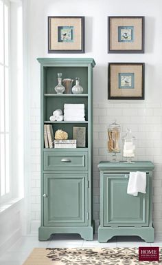 a bathroom with a green cabinet and pictures on the wall above it, along with a rug