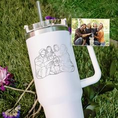 a white coffee mug sitting on top of a grass covered field next to a photo