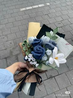 a bouquet of flowers sitting on top of a sidewalk next to a person's hand