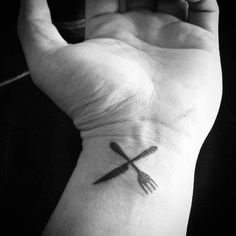 a black and white photo of a person's wrist with a knife tattoo on it