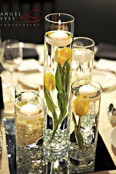 there are candles and flowers in the glass vases on the dining room table set for dinner