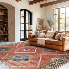 a living room filled with furniture and a large rug on top of a wooden floor