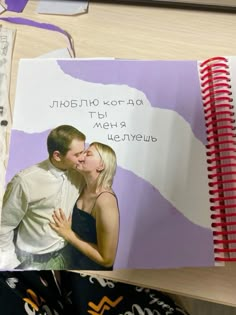 a couple kissing in front of a purple and white book with writing on the cover