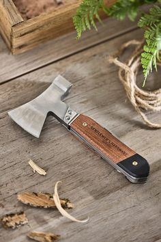 a knife that is sitting on top of a wooden table next to some leaves and a potted plant