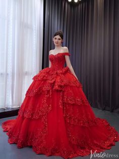 a woman in a red wedding dress standing next to a window with curtains behind her