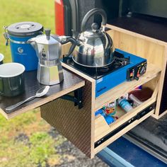 an open camper with pots and pans on the shelf next to the stove