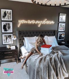 a woman sitting on top of a bed next to a wall with pictures above it