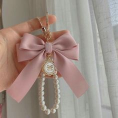 a hand holding a key chain with a bow on it