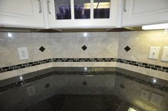 a kitchen with white cabinets and black granite counter tops in the center is an illuminated light switch