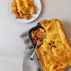 a table topped with a pie next to a white plate filled with food and a fork