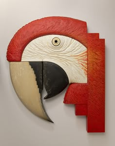 a red and white bird with a large beak on it's face is mounted to the wall