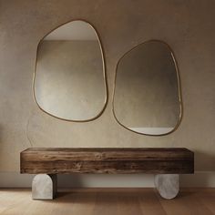 a wooden bench with two mirrors on the wall and a vase in front of it