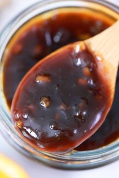 a wooden spoon full of bbq sauce on top of a glass jar filled with barbecue sauce