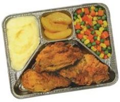 a tray filled with fried chicken, potatoes and carrots next to some other foods