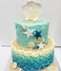 there is a blue and white cake with shells on it that has starfish, seashells, and seaweed