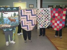 several people holding up quilts in a room