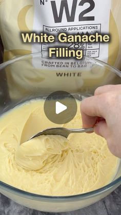 a person spooning batter into a bowl with w2 white ganache filling in it