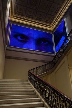 the stairs are covered with blue lights and there is a man's face projected on the wall