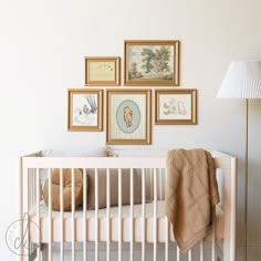 a white crib with pictures on the wall above it and a lamp next to it