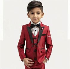 a young boy wearing a red suit and bow tie with his hands in his pockets