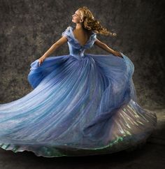 a woman in a blue dress is posing for a photo with her hair blowing in the wind