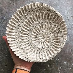 a hand holding a white plate on top of a cement floor