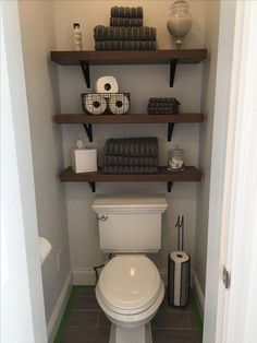 a toilet in a bathroom with shelves above it