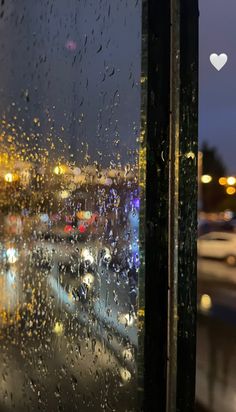 rain is falling on the window and cars are driving down the road in the distance